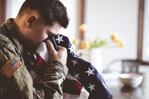 An American soldier mourning and praying with the American flag in his hands